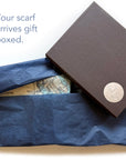 Gift box with blue tissue paper and a map, featuring a brand logo.