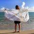 A person standing on a beach holding a white nautical chart towel with a map of Woods Hole to Cuttyhunk.